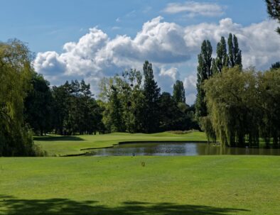 green du golf de saint-nom-la-breteche avec une étendue d'eau au fond