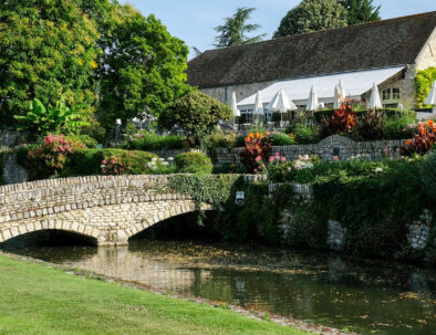 extérieur du golf de saint-nom-la-breteche avec un petit pont en pierre et des fleurs