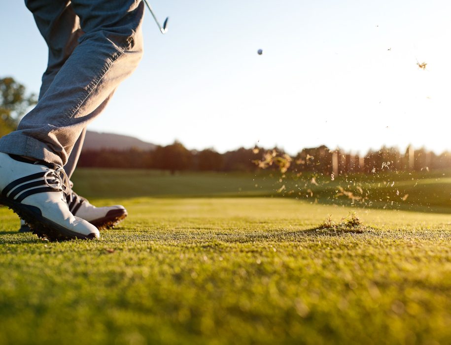 plan sur les pieds d'un golfeur qui vient de taper dans une balle avec son club sur un green